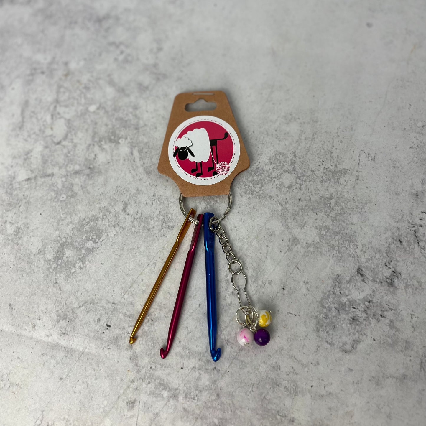 Mini Accessory keyring, shown with its packaging against a neutral background. You can see the three mini crochet hooks and safety pin with stitch markers.