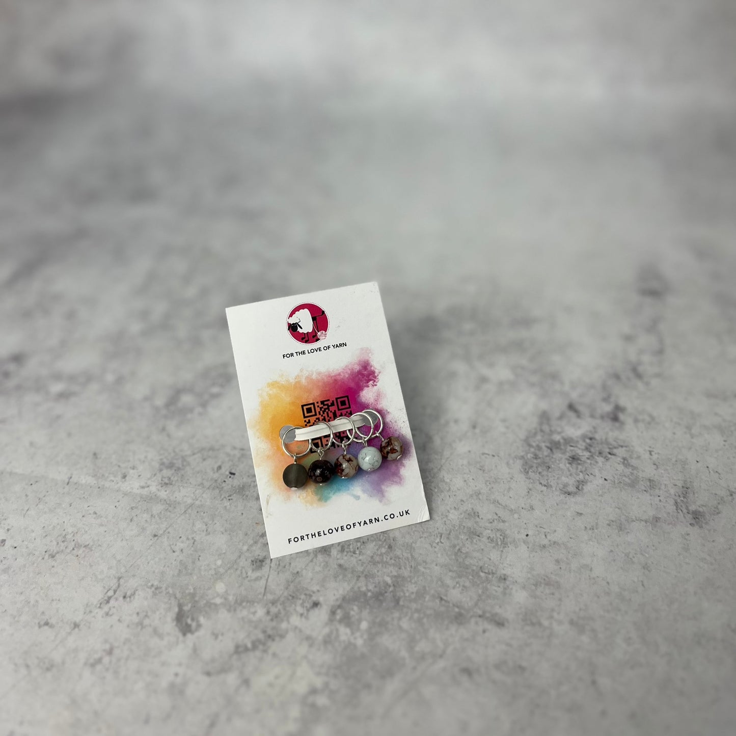 Set of neutral knit style stitch markers on backing card.