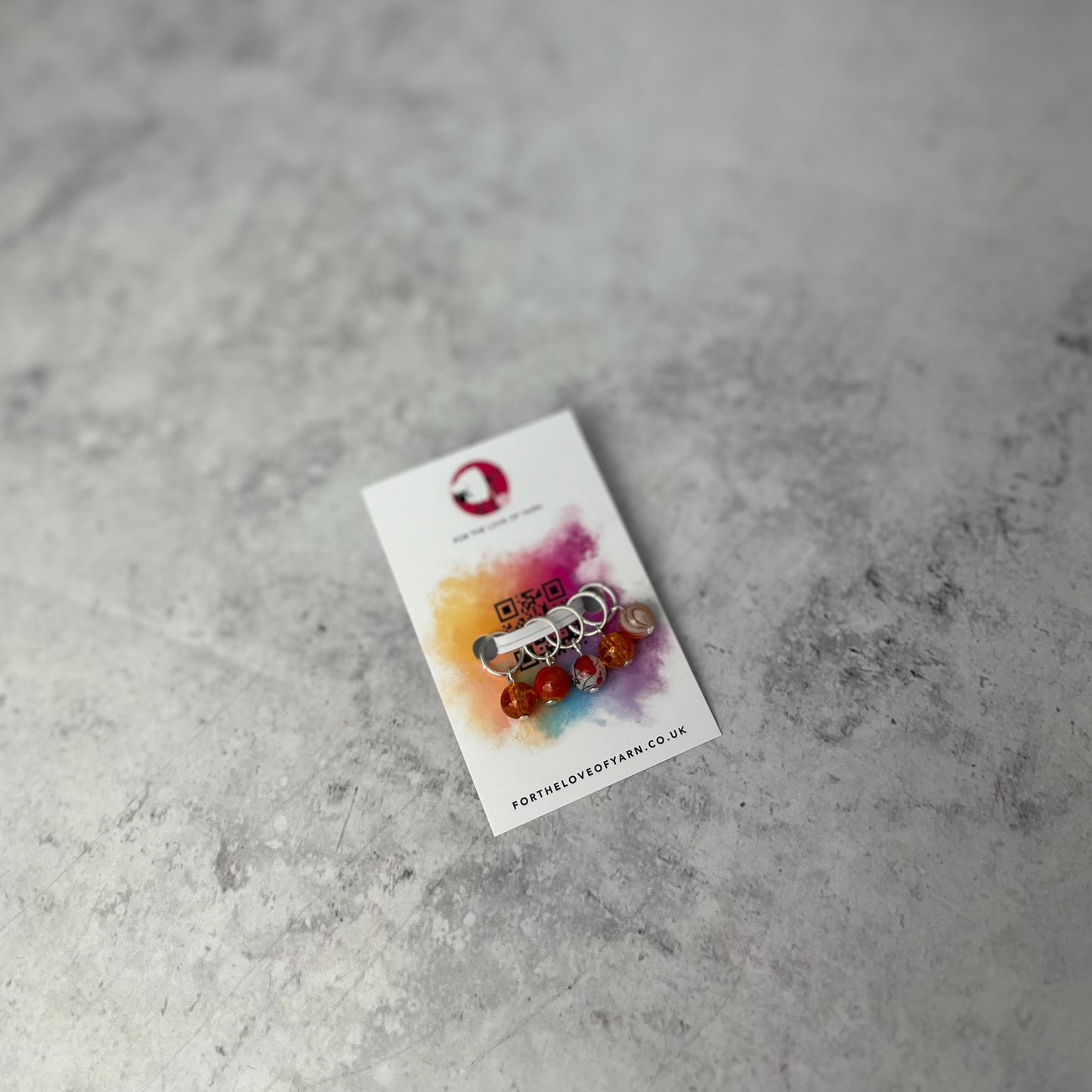 Set of orange knit style stitch markers on backing card.