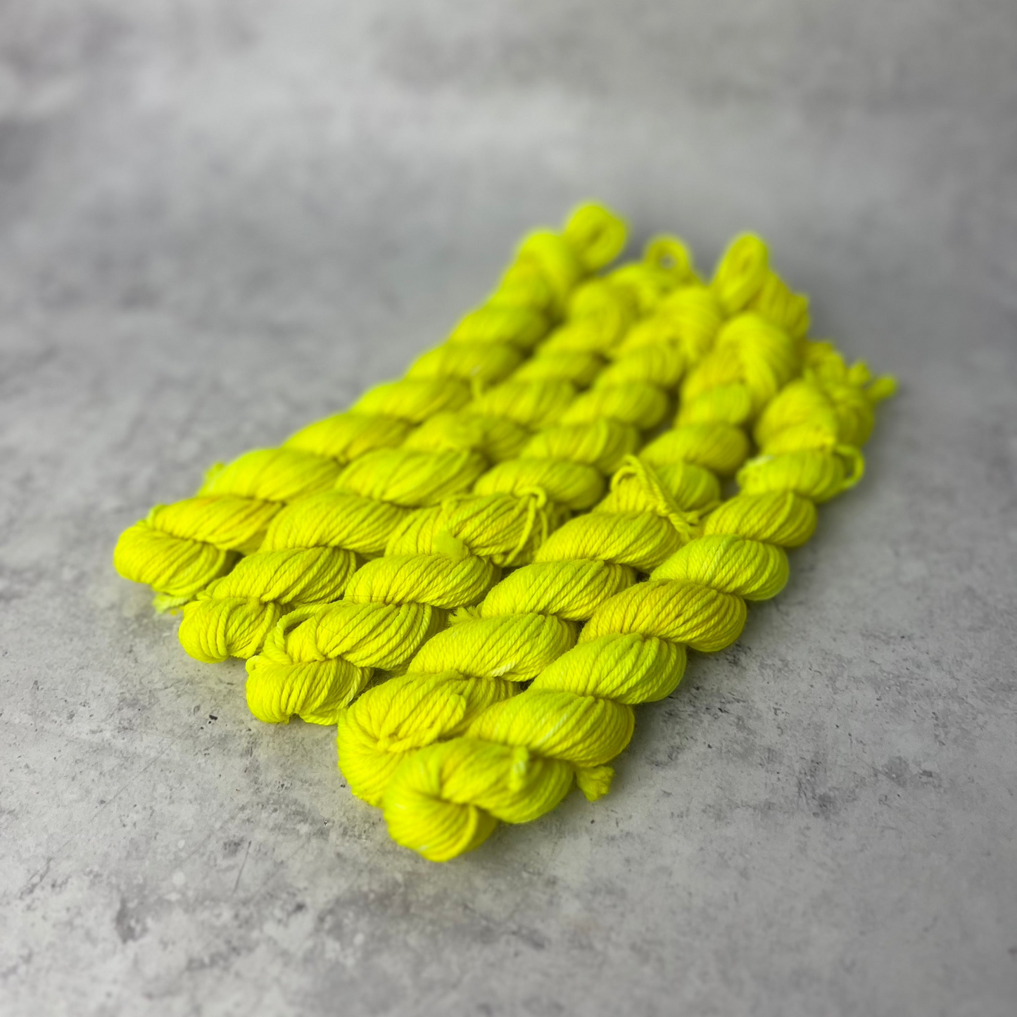 Yellow merino nylon mini skein shown against a neutral background.