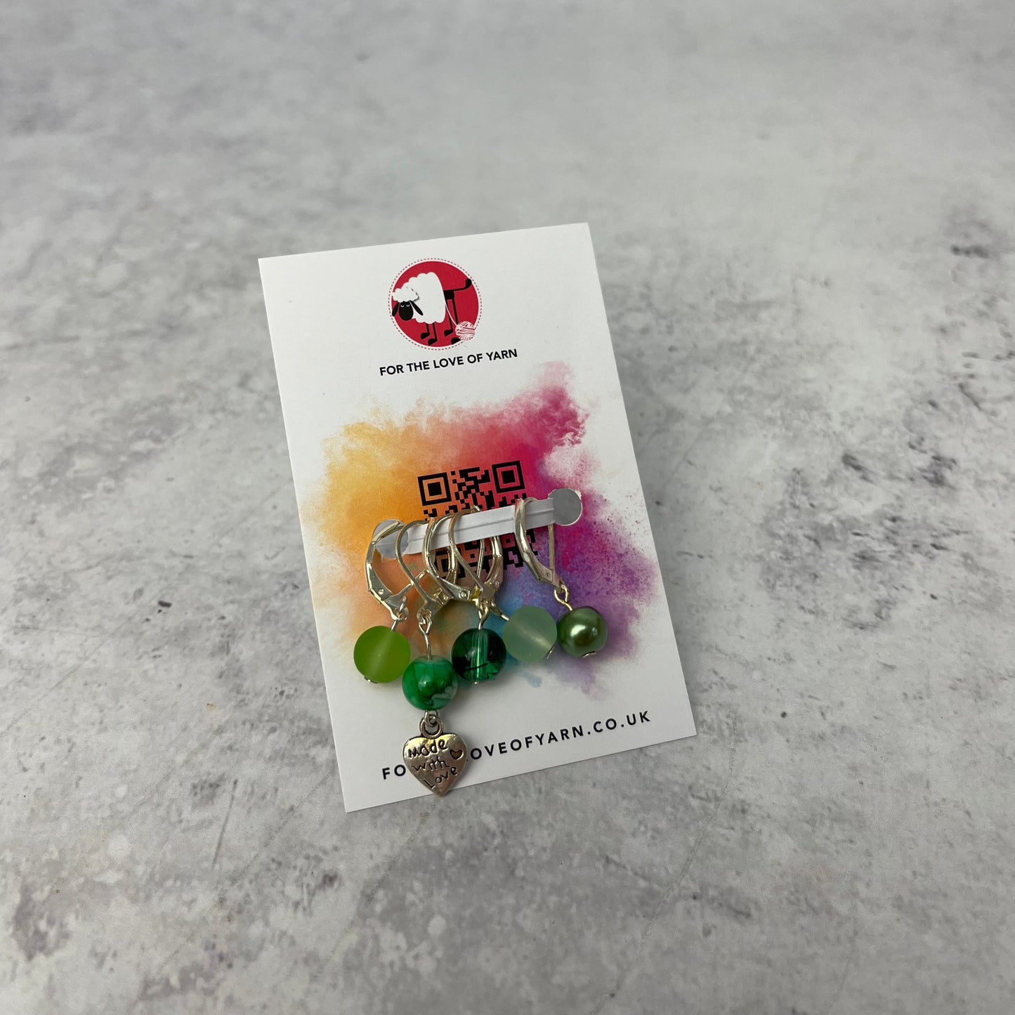 Set of green crochet style stitch markers on backing card.