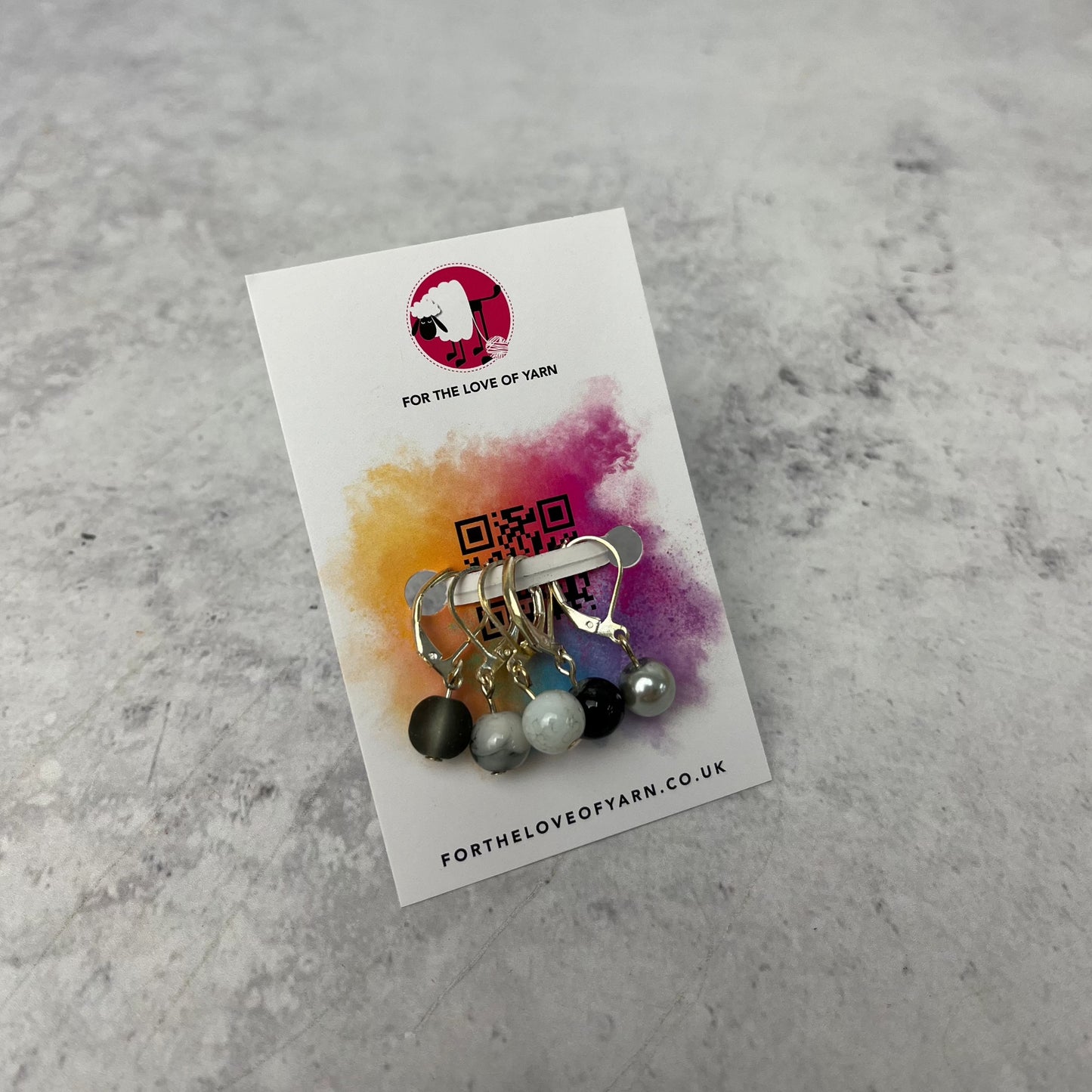 Set of neutral coloured crochet style stitch markers on backing card.