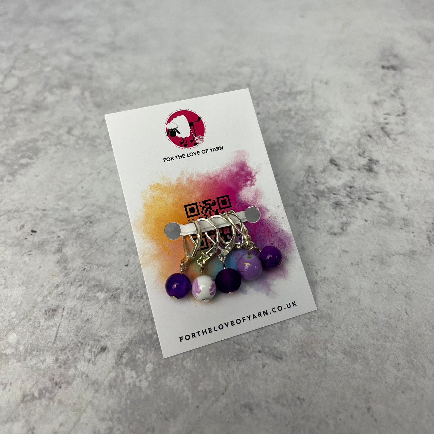Set of purple crochet style stitch markers on backing card.
