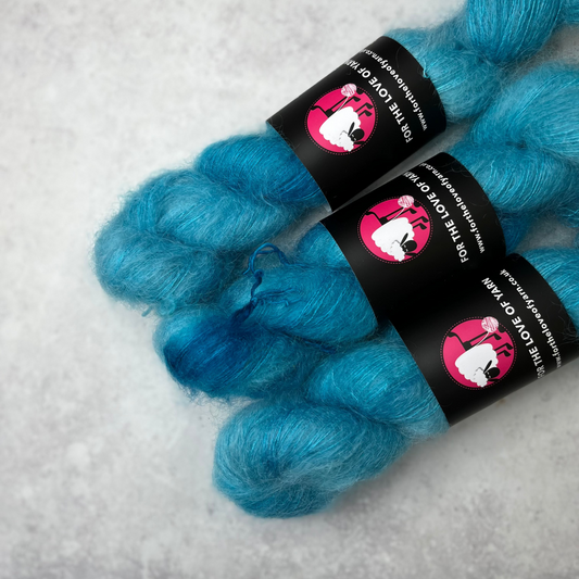 Three skeins of blue mohair against a grey background.