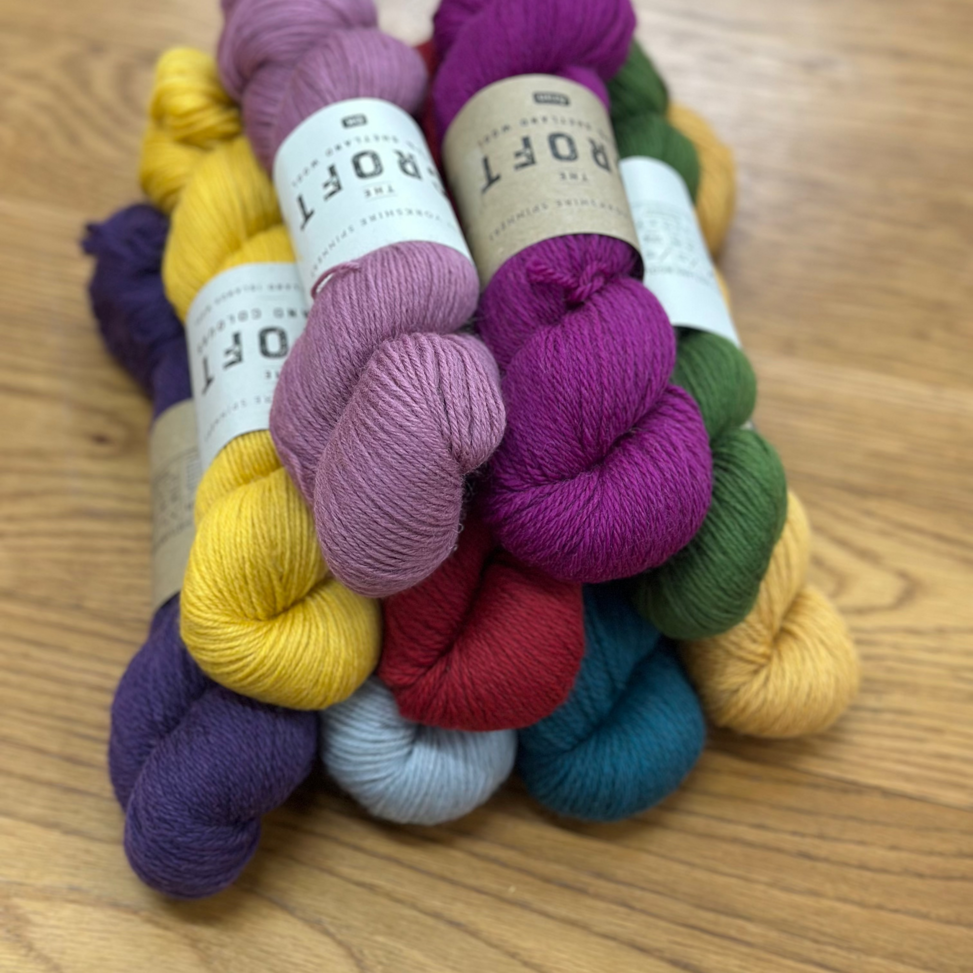 Colorful yarn skeins with 'Croft' labels on a wooden surface