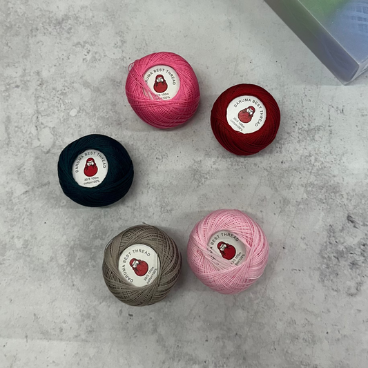 Five balls of yarn in different colors on a concrete surface