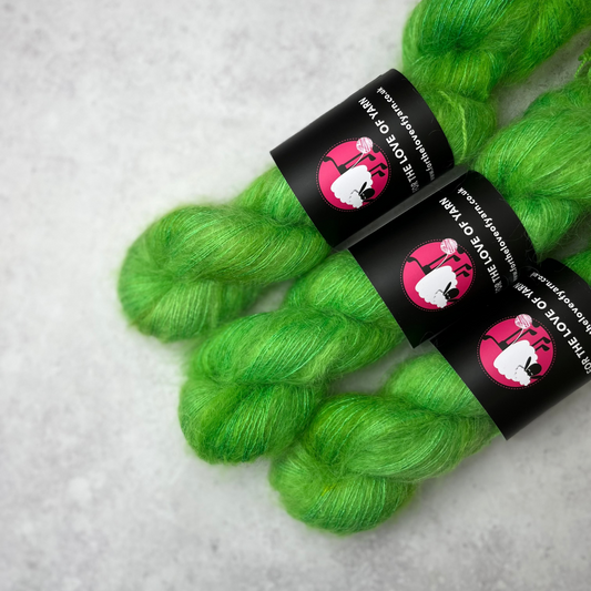Three skeins of green mohair against a grey background.