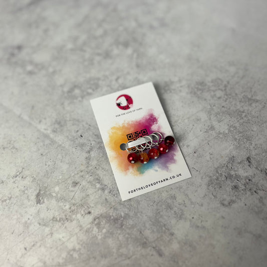Set of red  knit style stitch markers on backing card.