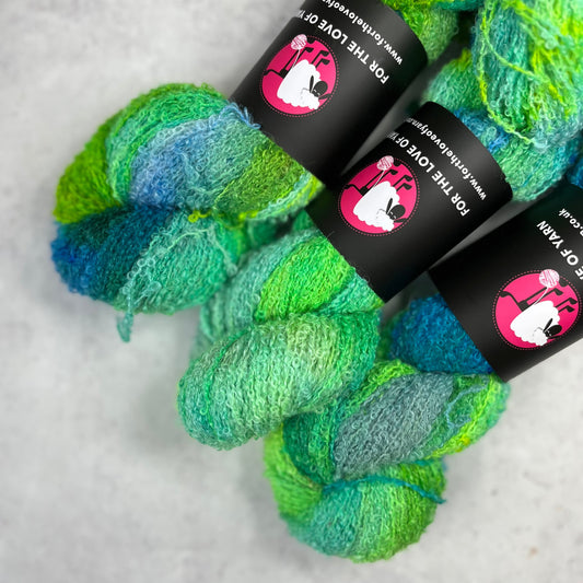 Blue and green skeins of baby alpaca silk boucle against a neutral background.