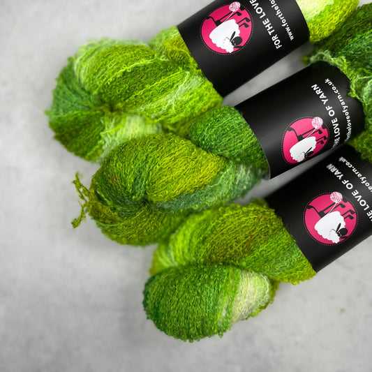 Three variegated green skeins against a neutral background.