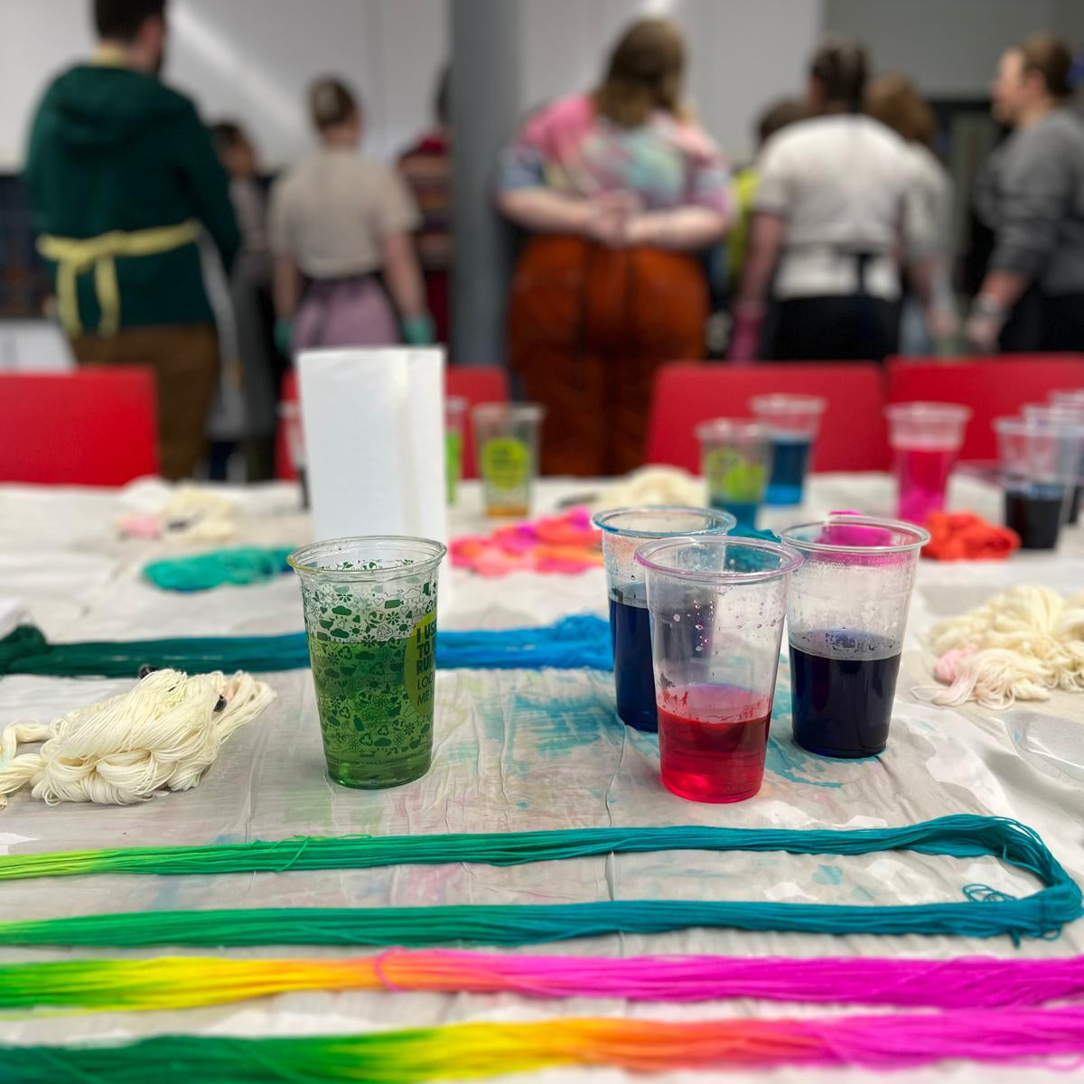 Table with colorful yarn and glasses of dyed yarn in a workshop setting