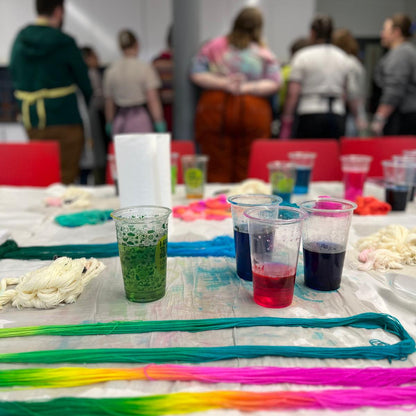 Table with colorful yarn and glasses of dyed yarn in a workshop setting