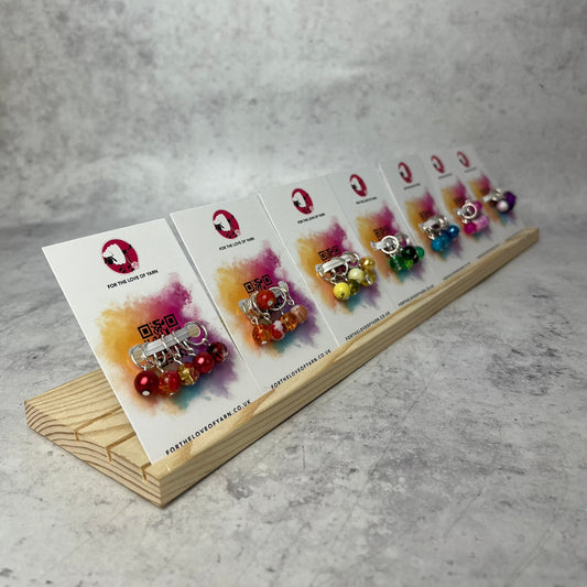 Row of knit stitch markers, showing the silver ring, sets organised in rainbow order.